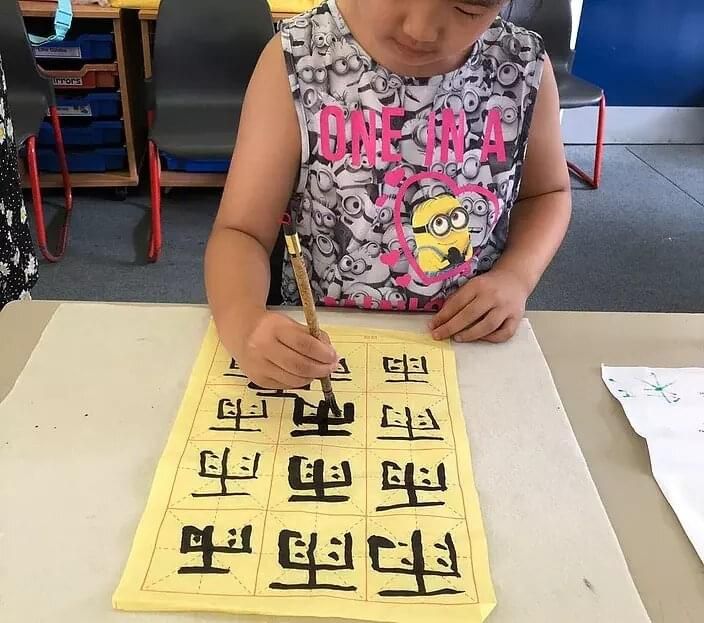 毛笔字 孩子用毛笔在米字格上写字
